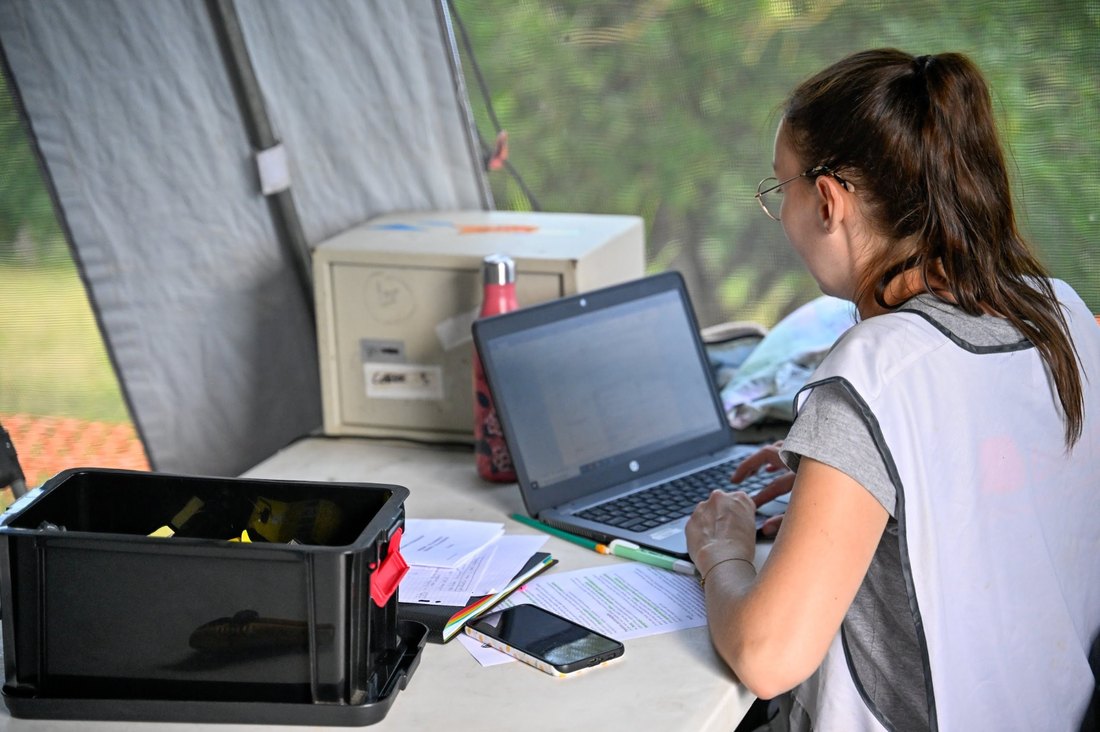 Étudiante Bioforce en poste logistique terrain avec ordinateur