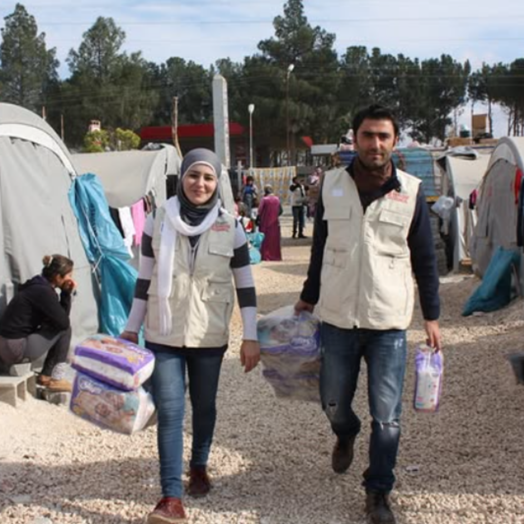 Deux personnes en mission humanitaire, entourés de tentes.