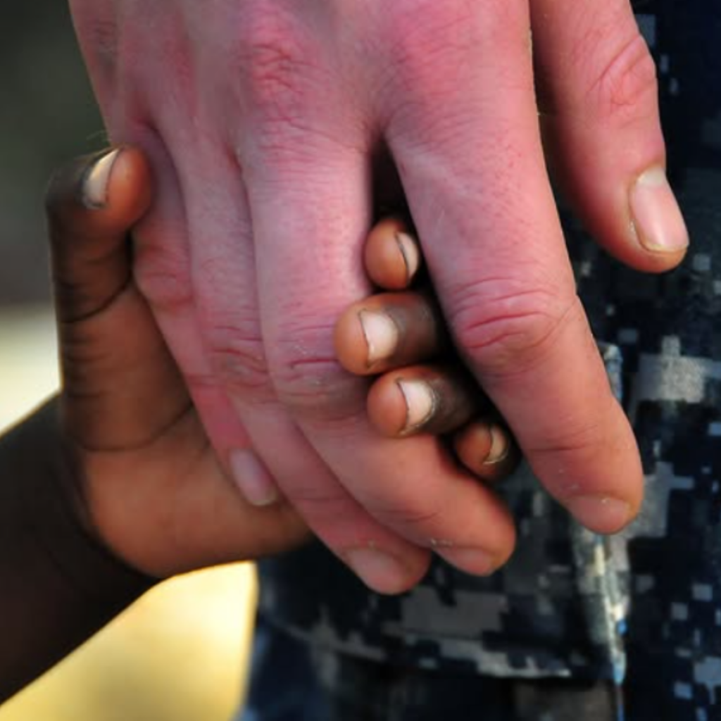 La main d’un adulte tenant celle d’un enfant.