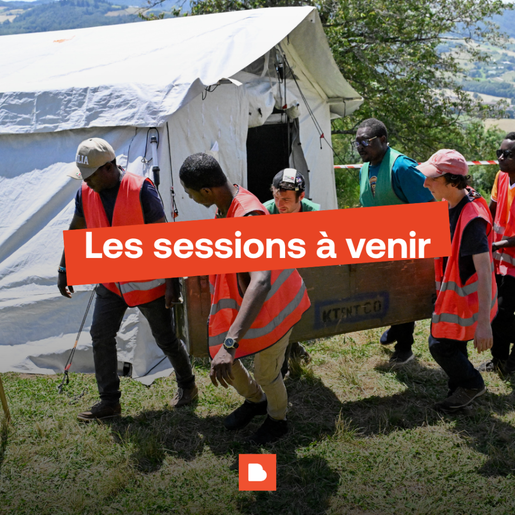 Plusieurs apprenants portant une caisse devant une tente : ils sont en simulation terrain.