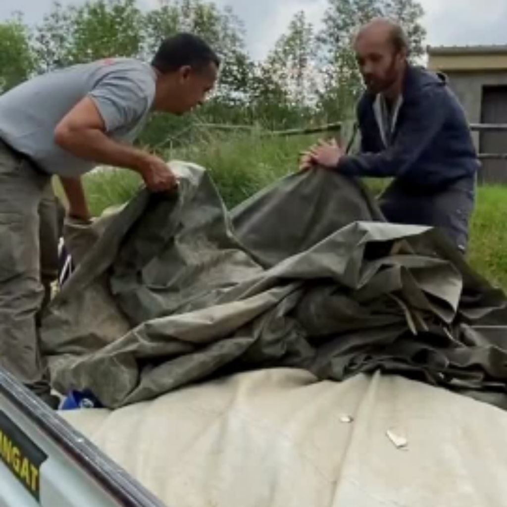 Deux personnes en simulation terrain, elles sont en train de récupérer du matériel sur un des véhicules Bioforce.